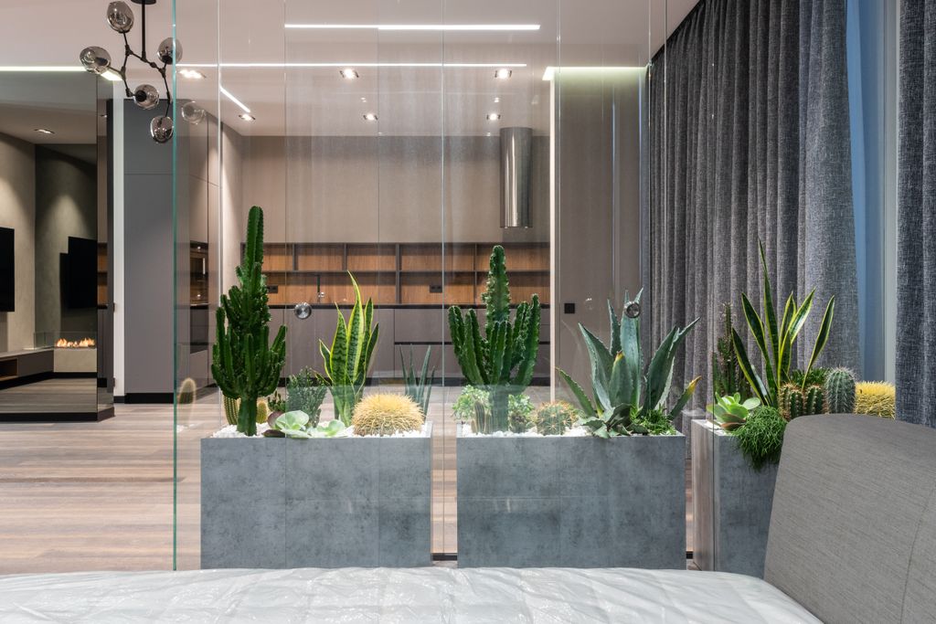 Interior of modern spacious lounge with small glasshouse for exotic plants between dining area and living room