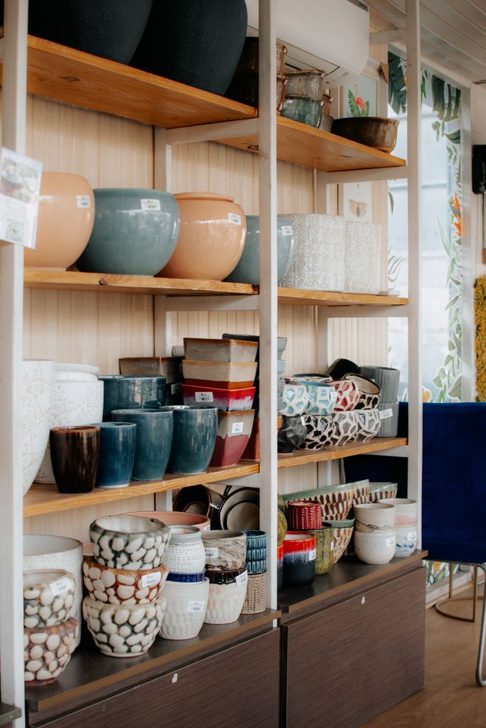 A collection of colorful ceramic pots and vases arranged neatly on wooden shelves in a store.