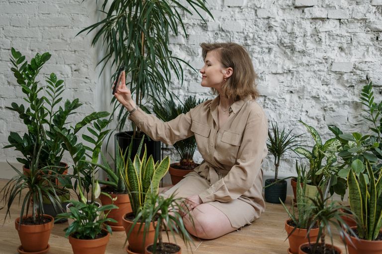 A woman takes a selfie while surrounded by various potted best indoor plants.